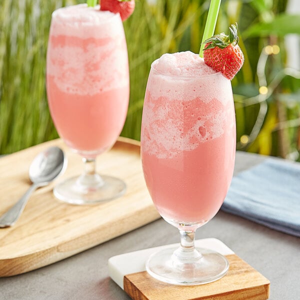 Two glasses of pink Fanale strawberry drinks with straws and strawberries on top.