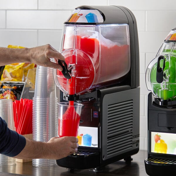 A man pouring a red drink into a Vollrath frozen beverage machine.