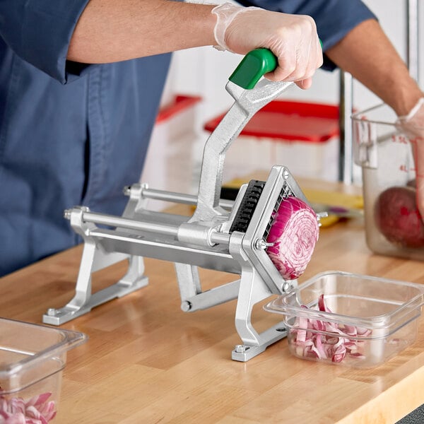 A person using a Garde table mount vegetable dicer with a green handle to cut a red onion.