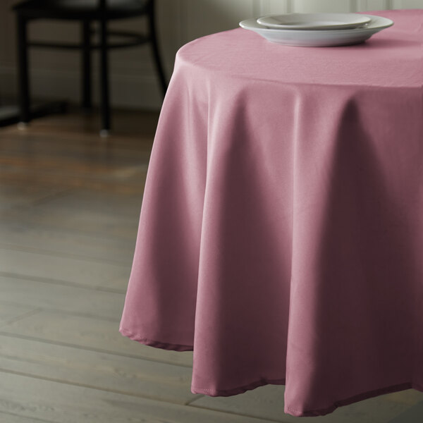 A round pink polyester table cover on a table in a restaurant.