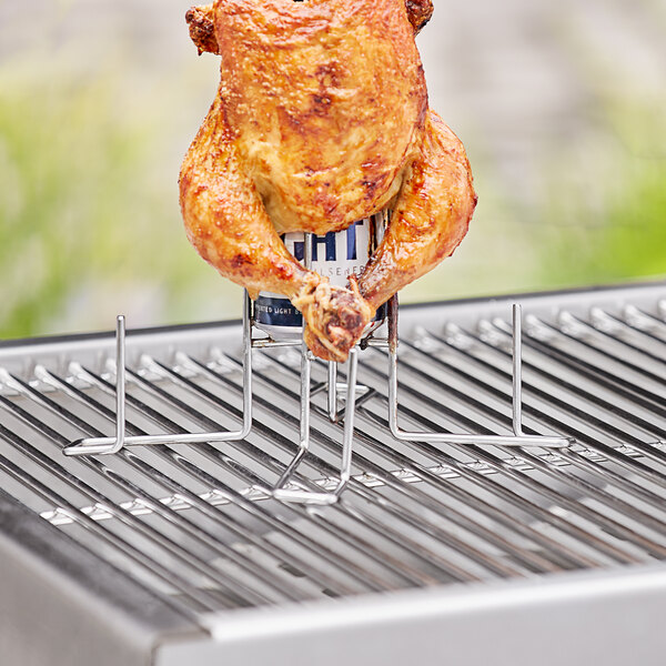A chicken on a grill with a stainless steel Outset beer can chicken roaster stand.