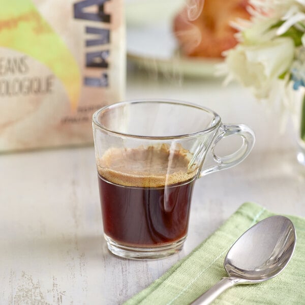 A glass cup of Lavazza Organic Tierra! Alteco whole bean espresso with a spoon on a table