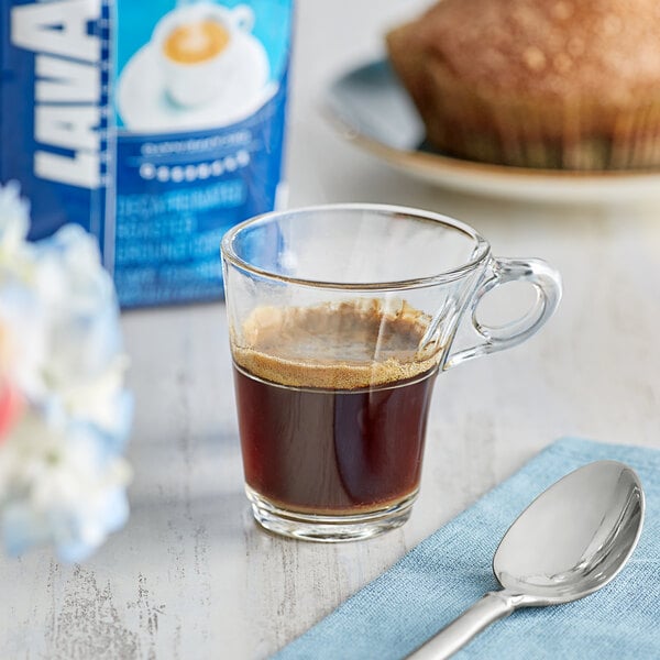 A glass cup of Lavazza Dek decaf espresso on a blue cloth with a spoon.