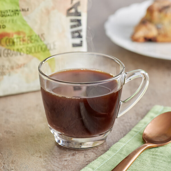 A glass cup of Lavazza Organic Tierra! Alteco coffee with a spoon on a napkin.