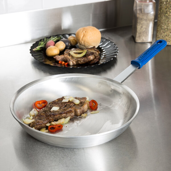 A Vollrath Wear-Ever aluminum fry pan with meat and vegetables cooking in it.