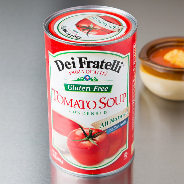 A can of Dei Fratelli condensed tomato soup next to a bowl of tomato soup.