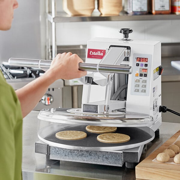 A woman using an Estella dual-heat dough press to bake cookies on a counter.
