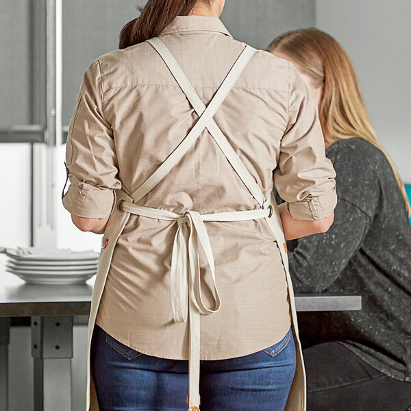 A woman's arm wearing Acopa Hazleton cream cross-back replacement straps over an apron.
