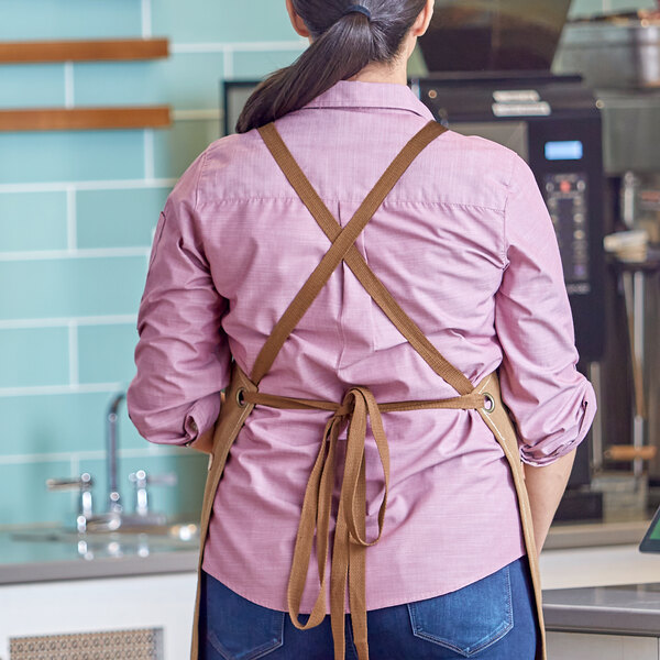 A woman wearing a brown Acopa apron with cross-back straps.