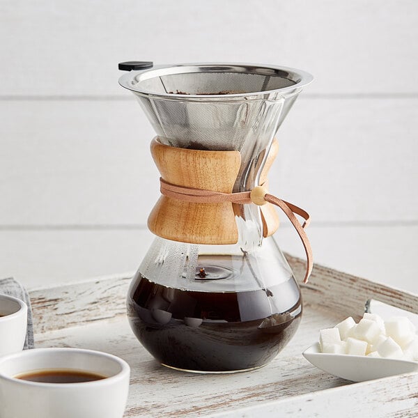 An Acopa glass coffee maker with a wooden collar and brown liquid.