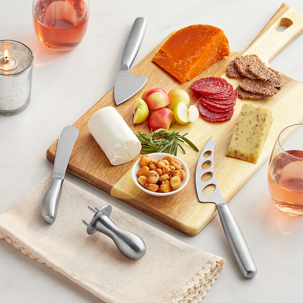 An Acopa stainless steel cheese knife on a wooden board with other food and wine.