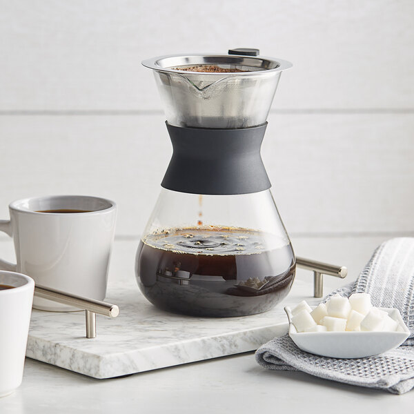 An Acopa glass pour over drip pot with coffee cups on a tray.