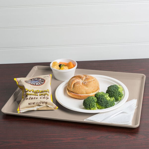 A Cambro taupe dietary tray with a sandwich and vegetables on it.