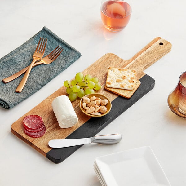 An Acopa acacia wood and slate serving board with cheese, grapes, and crackers on it.