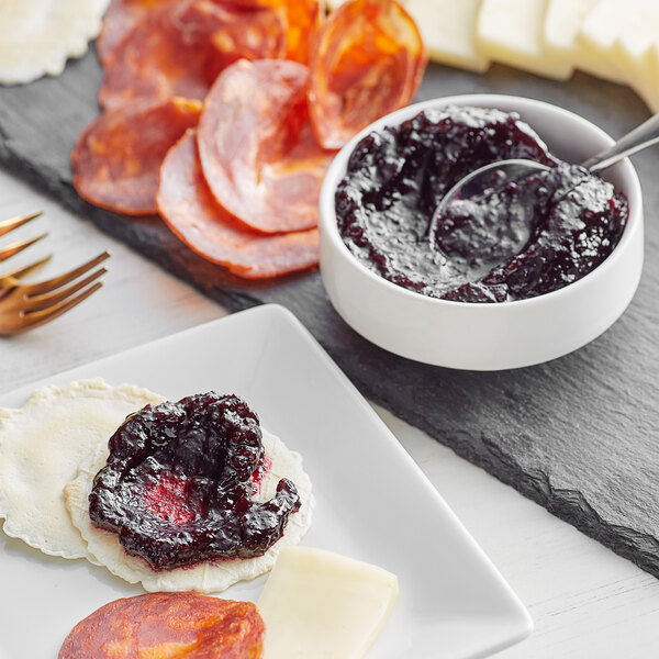 A plate of food with cheese, meat, and Dalmatia Organic Super Berry Spread.
