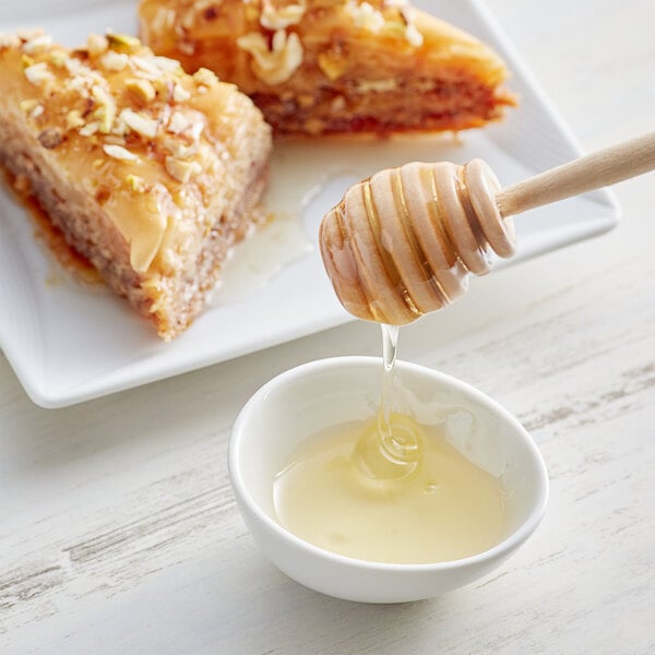 A piece of cake with honey on a plate with a honey dipper.
