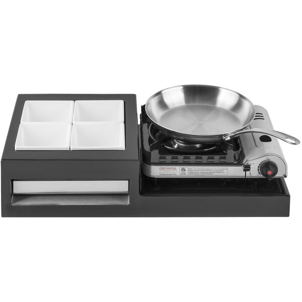 A black Tablecraft brushed aluminum single butane action station on a counter with a pan.