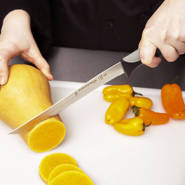 A person using a Dexter-Russell V-Lo scalloped utility knife to cut a squash.