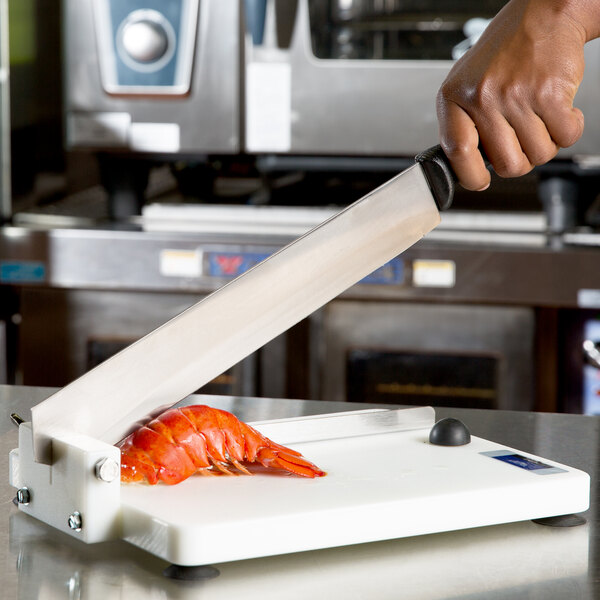 A person using a Vollrath Lobster King cutter to cut a lobster.