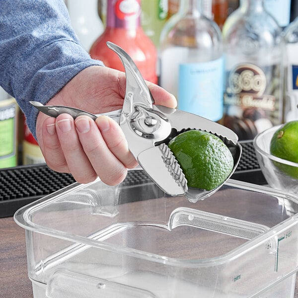 A person using a Choice stainless steel citrus juicer to squeeze lime juice.