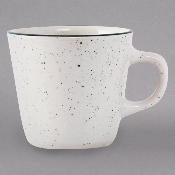 A white Tuxton tall cup with black speckles.