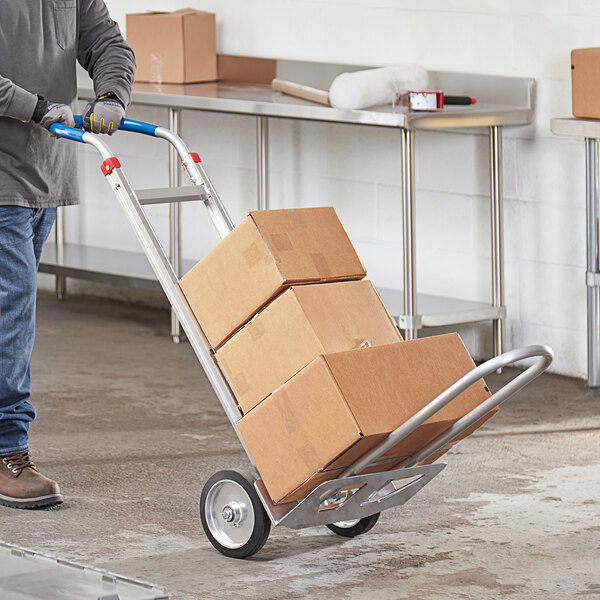 A man pushing a Lavex hand truck with a stack of cardboard boxes on it.