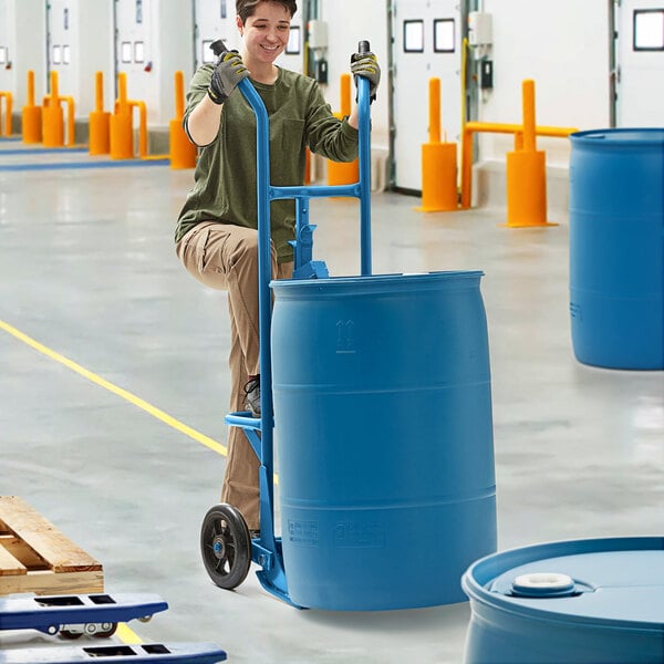 A man using a Lavex heavy-duty steel drum truck to move a blue barrel.