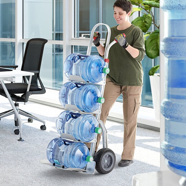 A woman using a Lavex aluminum hand truck to move water bottles.