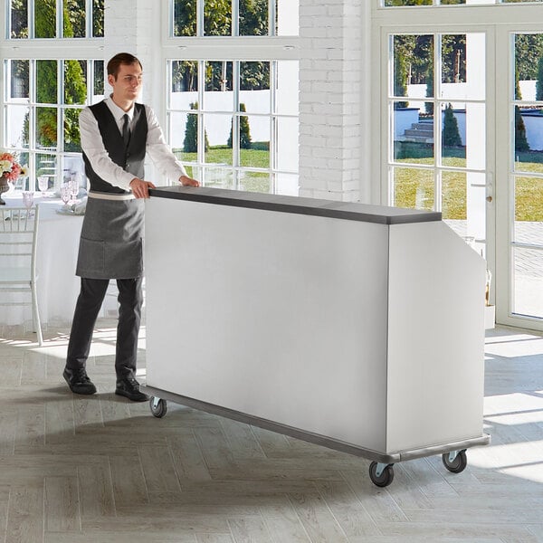 A man using a Regency stainless steel portable bar with ice bin and speed rails.