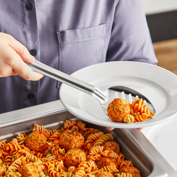 A person using a Choice slotted spoon to serve pasta with meatballs and sauce.