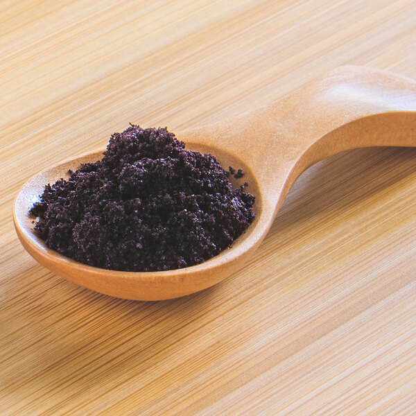 A wooden spoon filled with Organic Acai Powder.