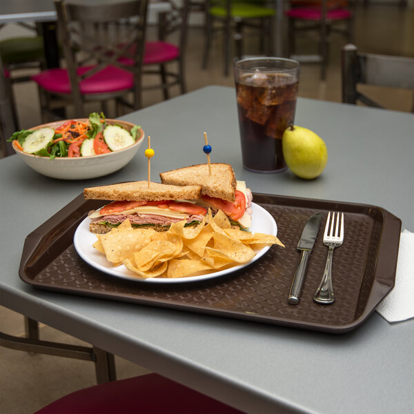 A Carlisle chocolate brown fast food tray with a sandwich and chips on it.