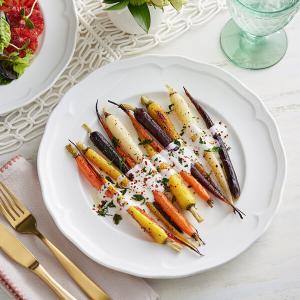 A white Acopa Condesa porcelain plate with carrots and salad on it.