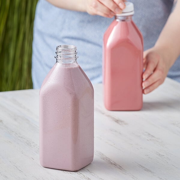A woman pouring pink milk into a customizable square PET bottle.