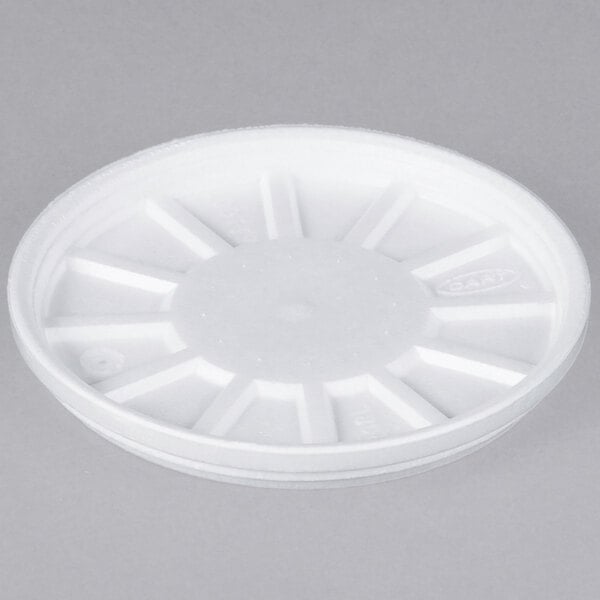 A white foam lid with a cross pattern and circles with holes in them.