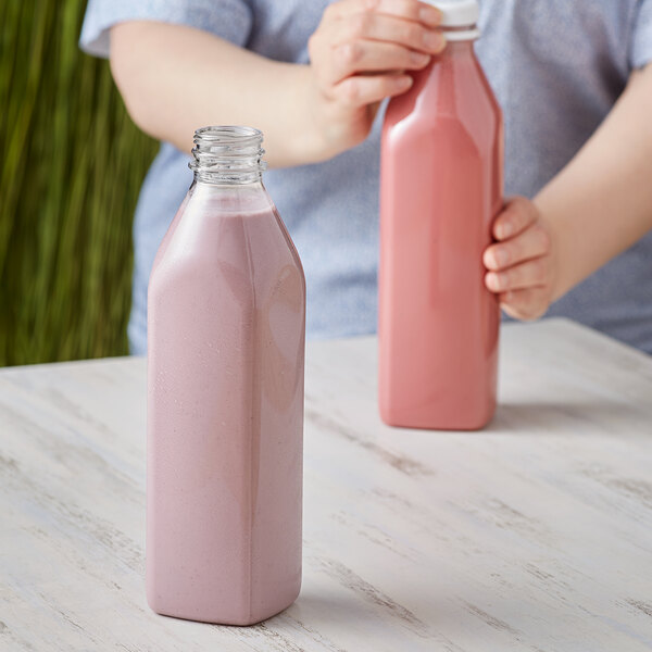 A woman holding a customizable tall square clear plastic bottle filled with pink liquid.