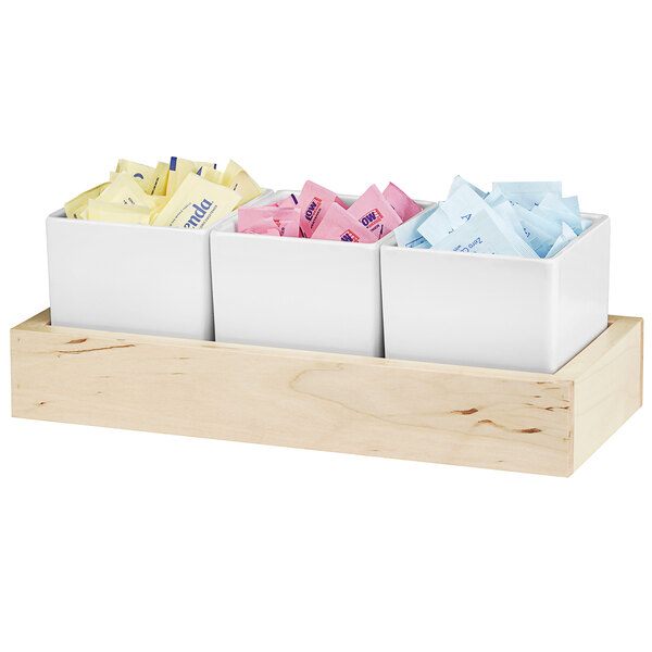 A Cal-Mil condiment organizer with three melamine jars holding sugar packets, white and pink.