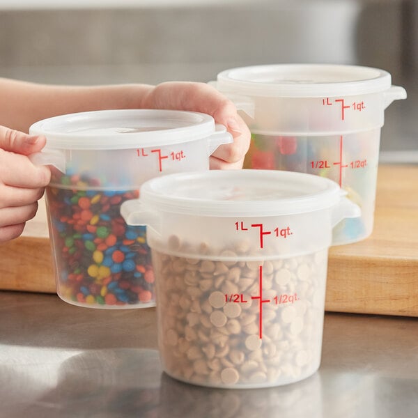 A hand using a measuring cup to fill a Choice translucent plastic food storage container.
