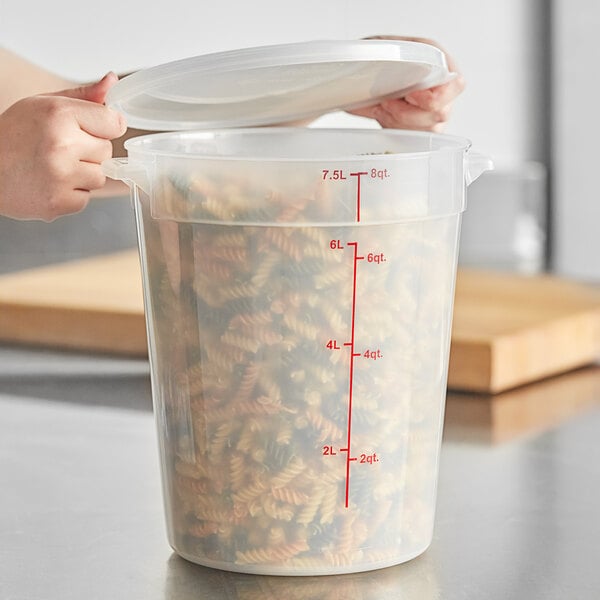 A translucent round polypropylene food storage container with spiral pasta in it and the lid open.