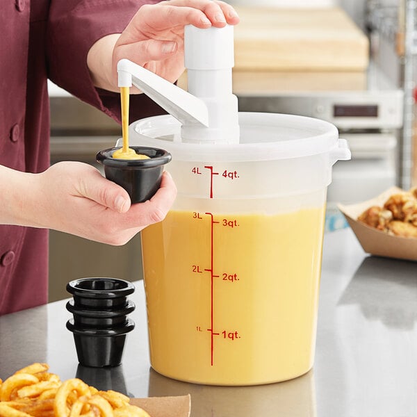 A person using a Choice condiment pump to pour yellow liquid into a black container.