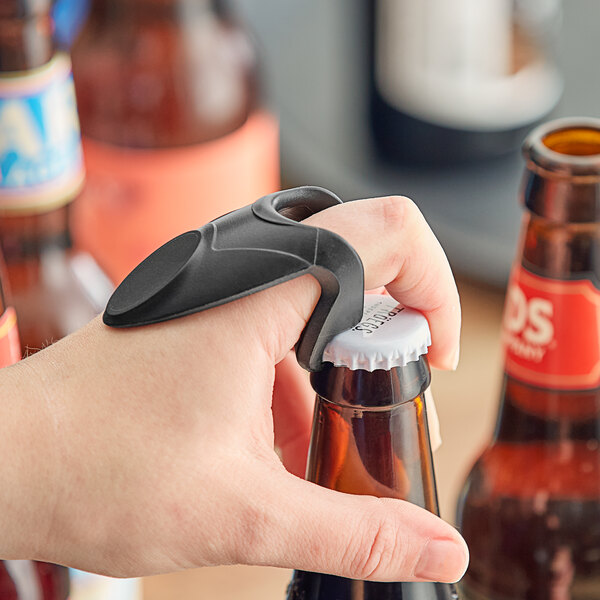 A person using a Franmara black plastic knuckle bottle opener to open a bottle on a counter.