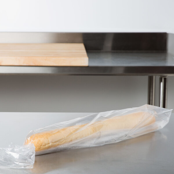 A baguette in a LK Packaging plastic bag on a wooden board.