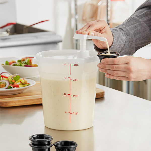 A woman using a Choice condiment pump to pour white liquid into a container of salad.