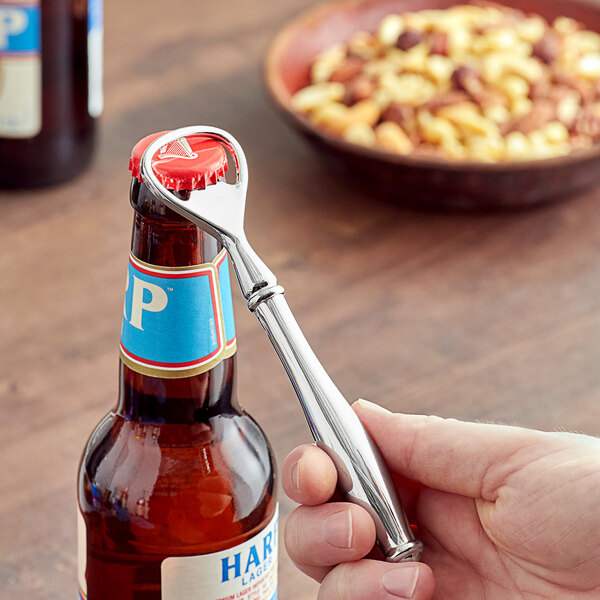 A person holding a Franmara silver-plated bottle opener over a bottle on a counter.