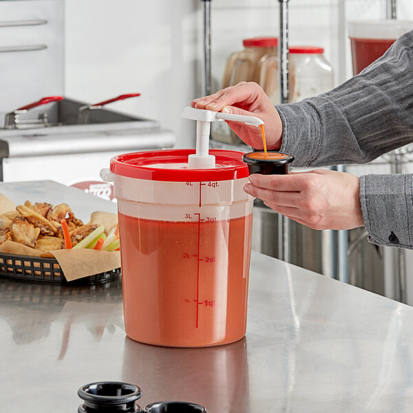 A person using a Choice condiment pump to pour red liquid into a plastic container with a red lid.