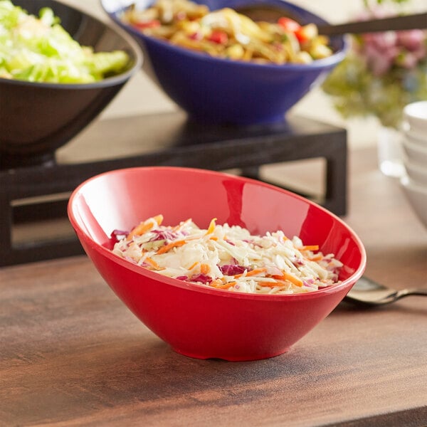 A red Acopa melamine bowl filled with salad and coleslaw.