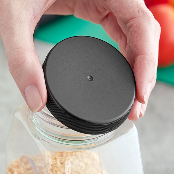 A hand holding a jar with a black 63/400 unlined ribbed plastic cap.