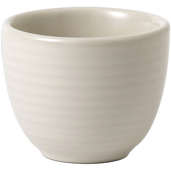 A close up of a Dudson Evo matte pearl white stoneware taster cup with a curved pattern and a handle.