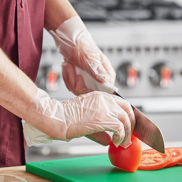 A person wearing Noble NexGen TPE gloves cutting a tomato.