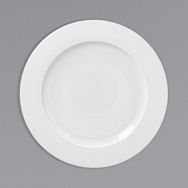 A white RAK Porcelain flat plate with a white rim on a gray background.